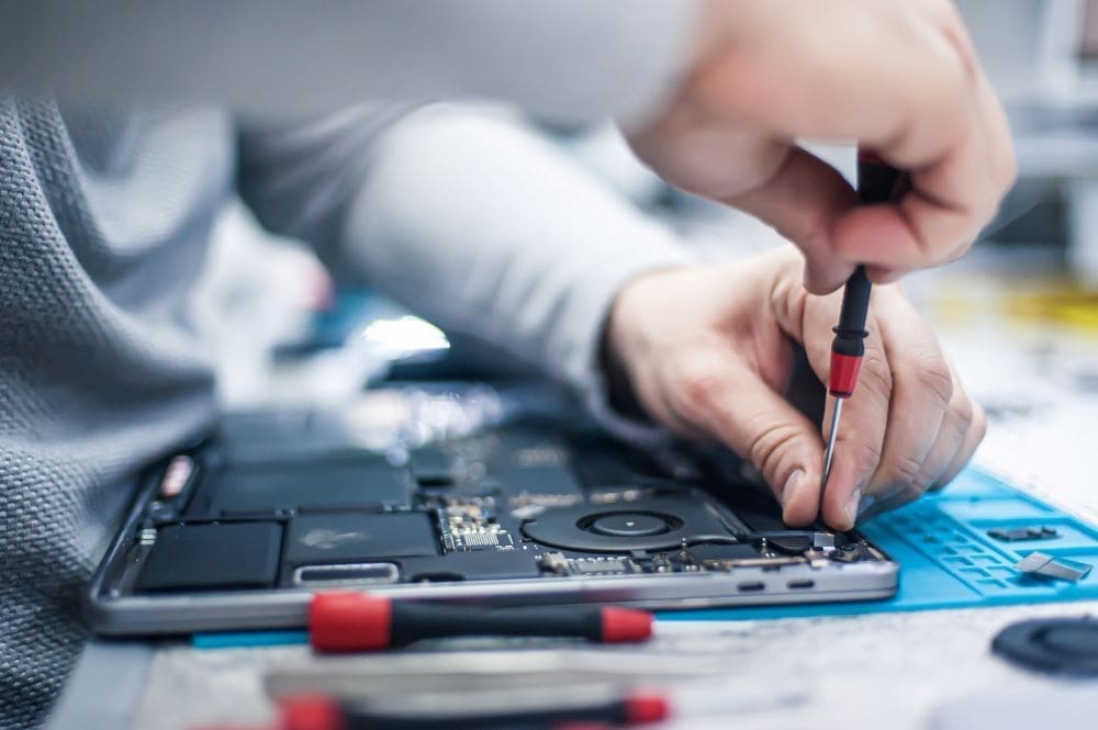 A professional computer repair service member repairing an apple computer.