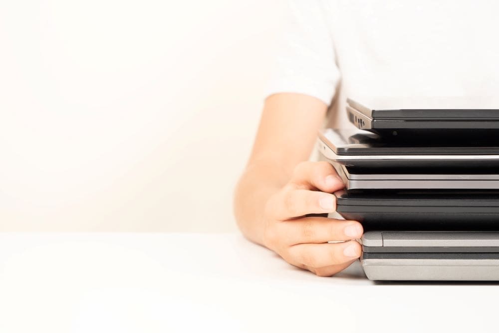 A woman holding her old laptops and getting them ready for a laptop trade-in.