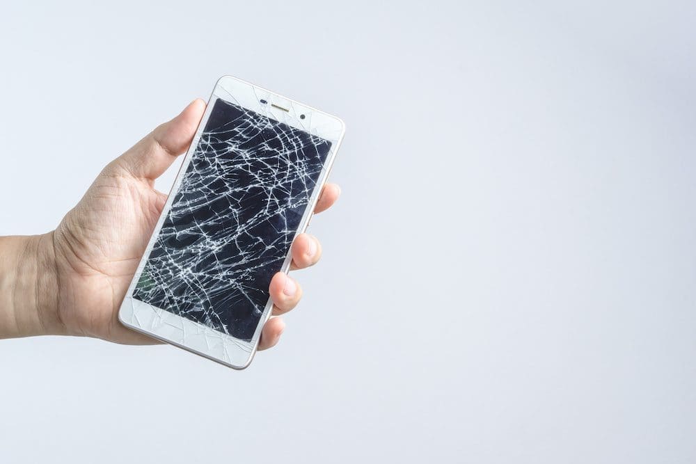 A person holding an iphone with broken screen.