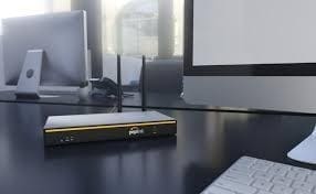 Router on desk with computer monitor.