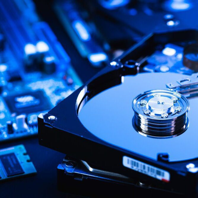 Hard disk drive on the technician's desk and a computer motherboard as a component.